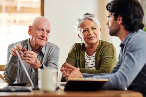 Senior couple speaking to their financial adviser at home 