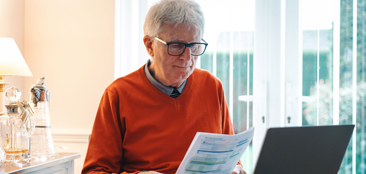 Senior man in his 70s checking his energy bills at home.